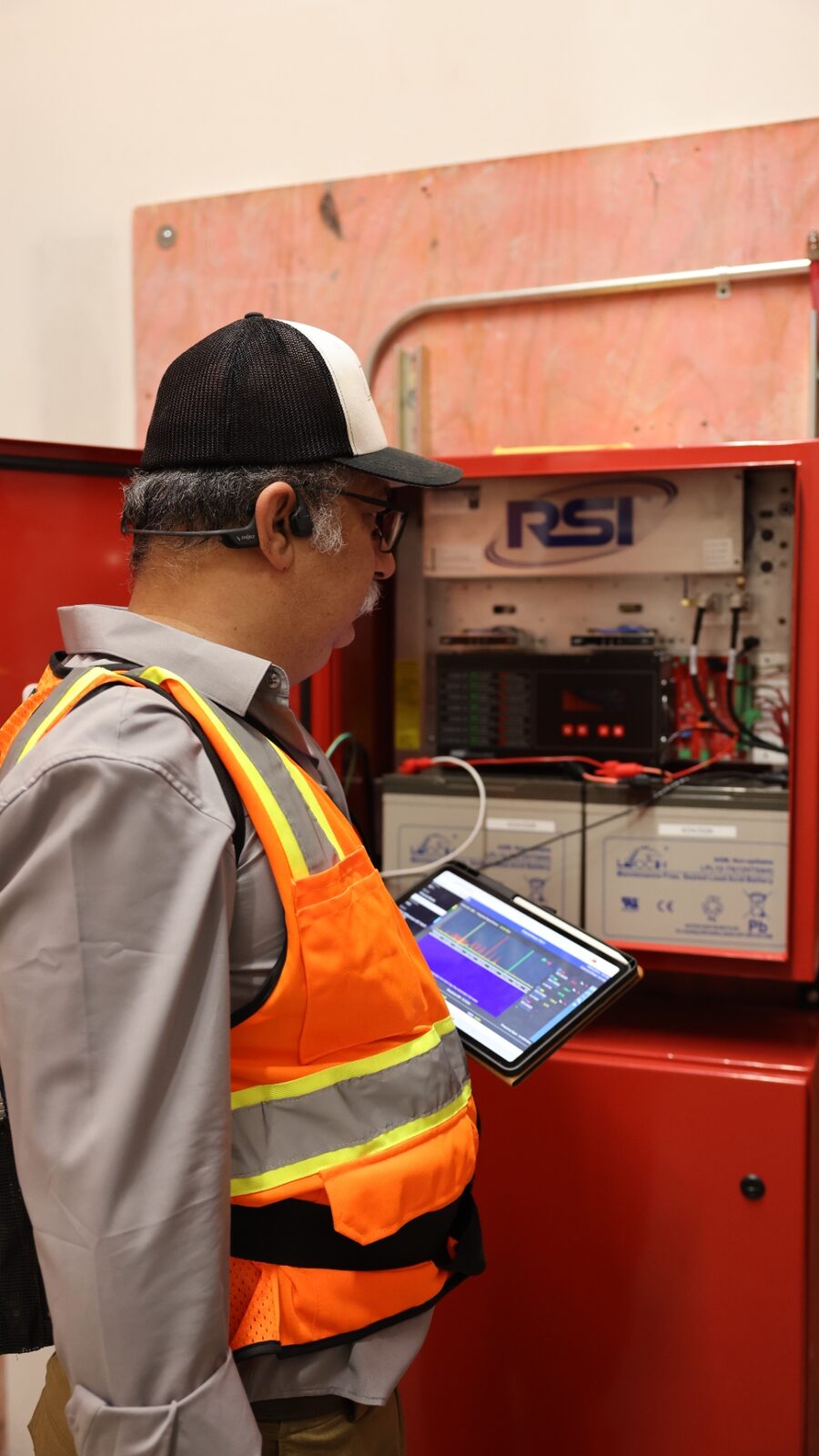 Zion technician commissioning an RSI public-safety BDA — RSI cabinet open, spectrum analyzer running on tablet
