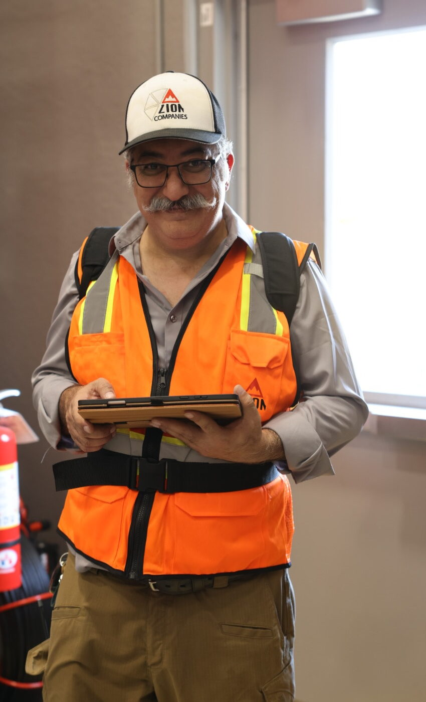 Joel Sadowsky wearing Zion cap and high-visibility vest, performing commissioning with a tablet
